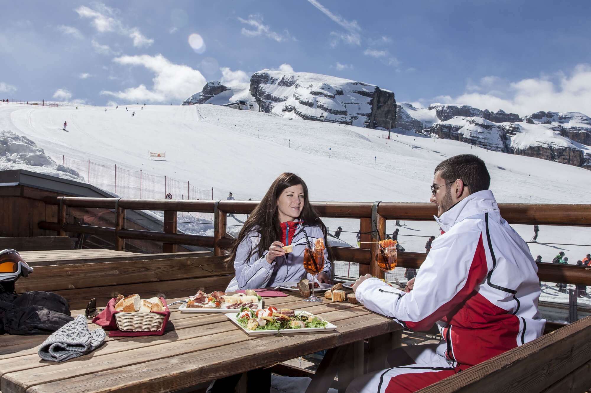 Due persone mangiano su un tavolo con vista su montagne innevate.